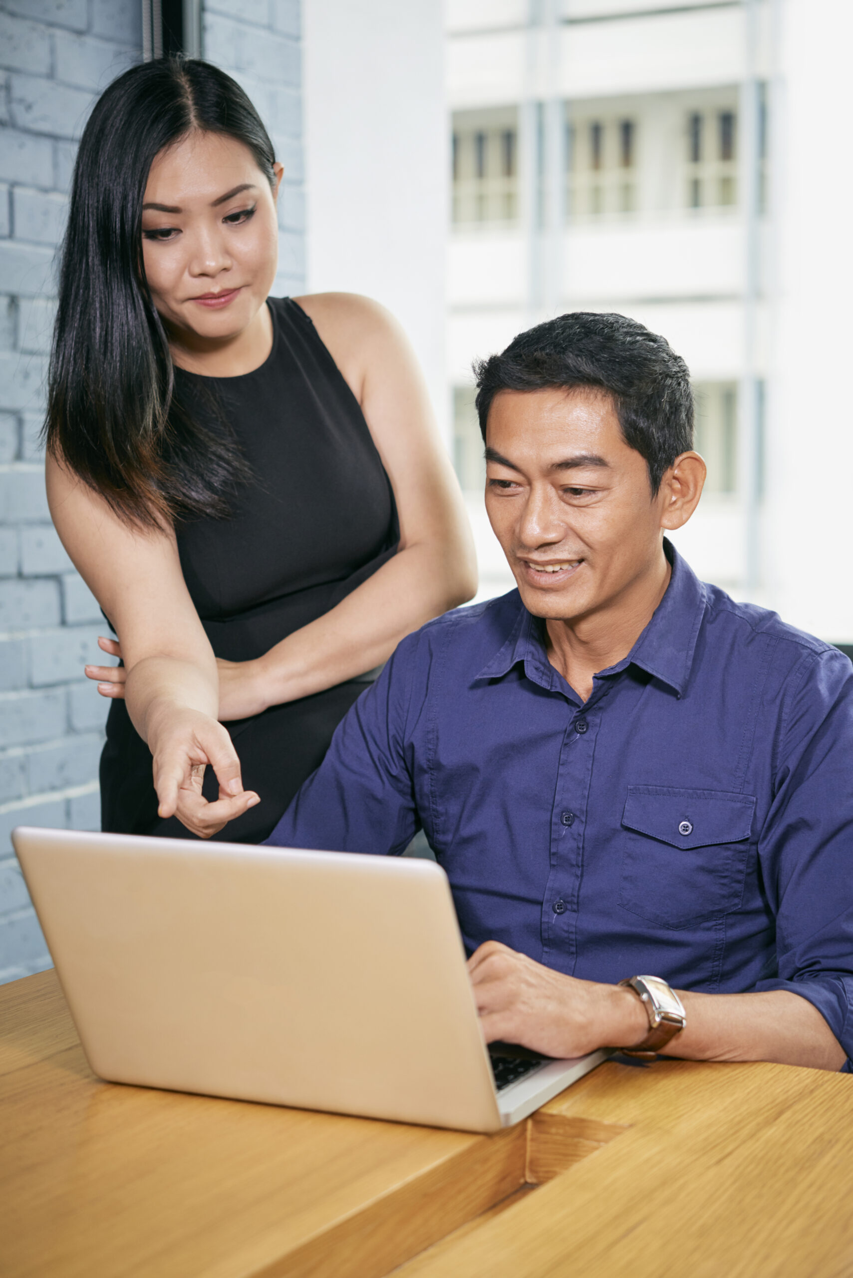 Smiling businessowoman helping her colleague with work
